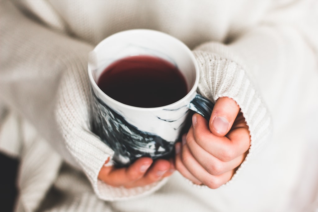 温かい飲み物を両手で包むように持つ人