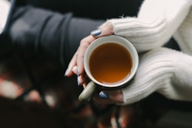 両手で温かいお茶のカップを包む様子