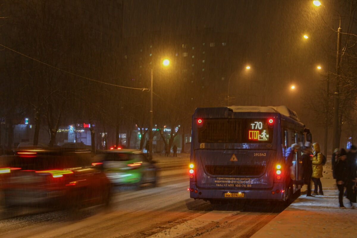 雪の降る夜の道を走るバス