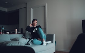 自宅のソファでスマートフォンを手にする女性